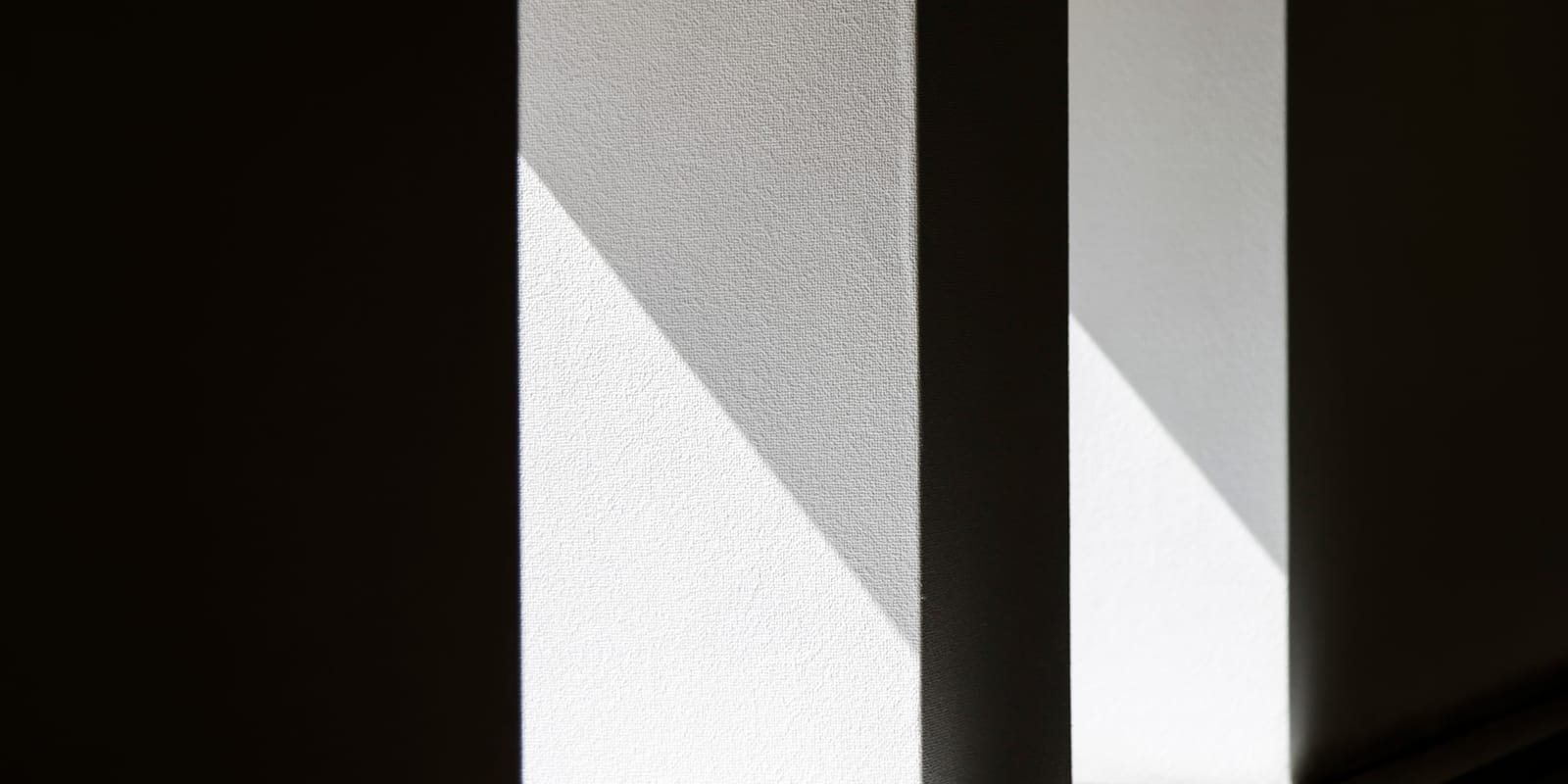 A tall concrete pillar lit from the side, its edge a clean line between light and shadow.