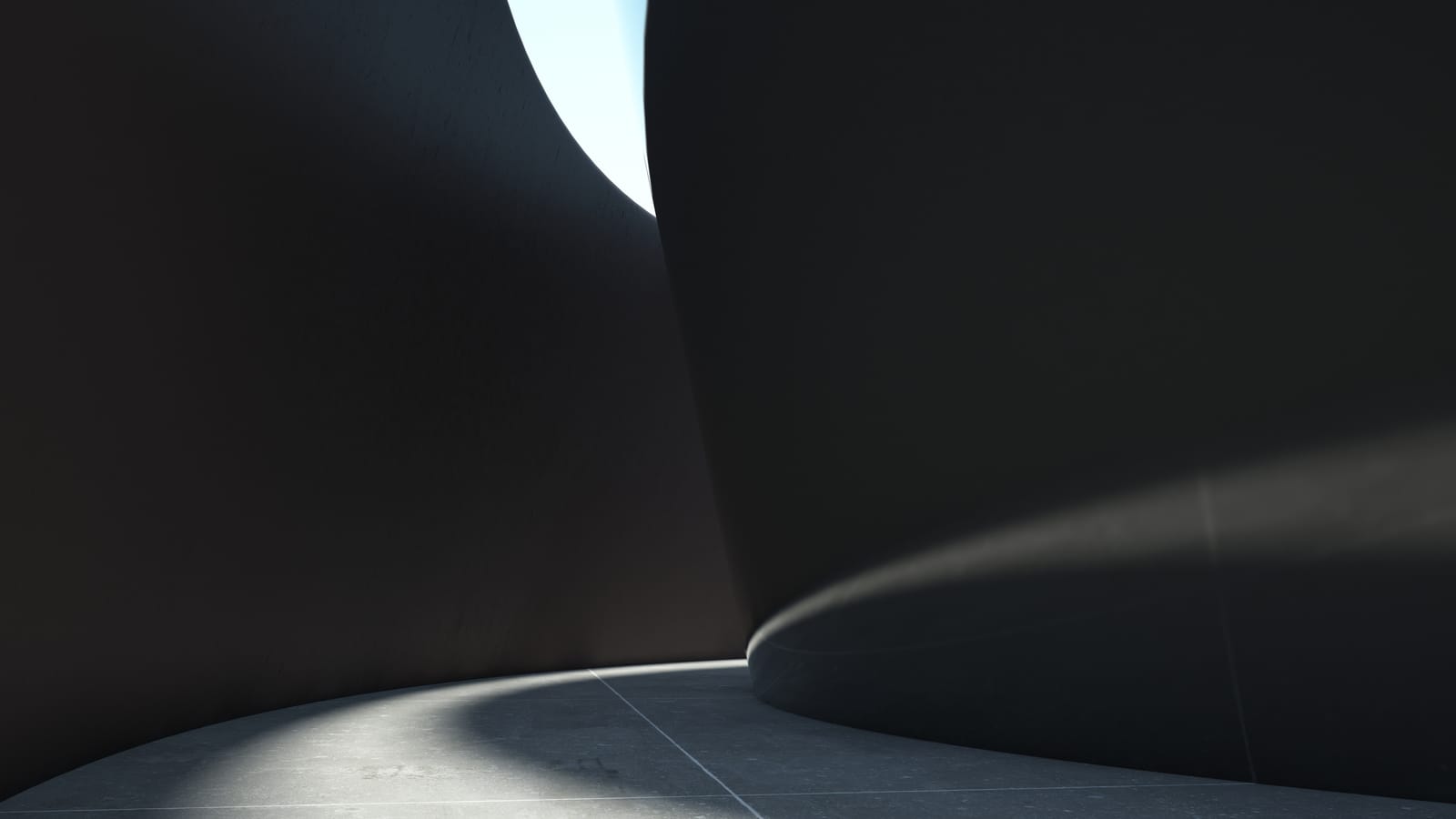 A concrete passage lit from one side, light falling across its walls in sharp geometric bands.